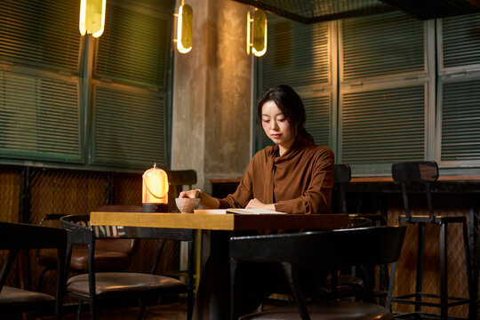 A woman enjoys a cup of tea and a good book at a serene tea house
