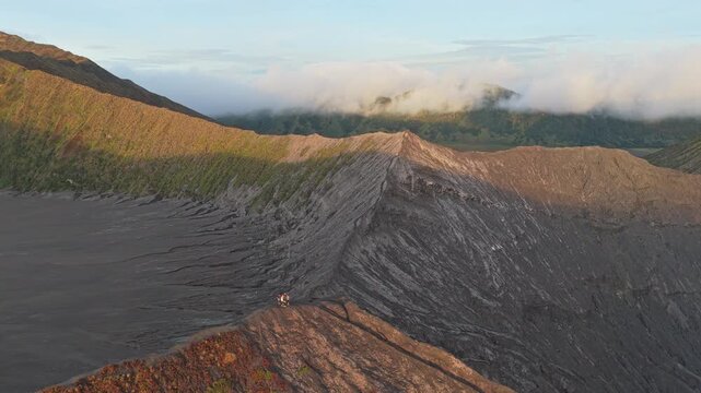 People standing on smoking bromo volcano crater rim in indonesia