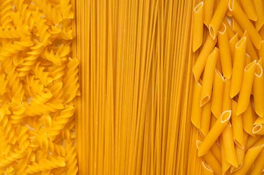 Background of uncooked macaroni of various shapes. Italian pasta close-up. Fusilli, penne pasta, spaghetti. Healthy food made from wheat flour