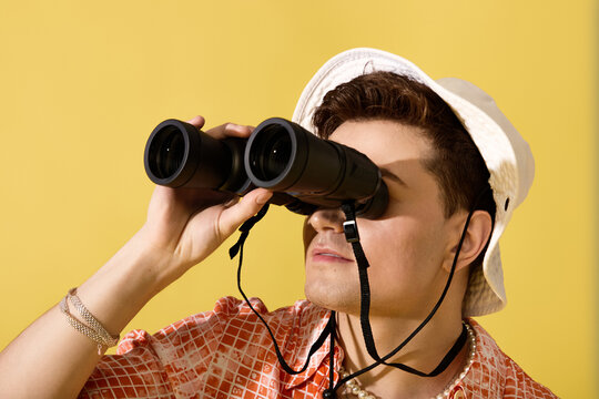 Charming young man observing the vibrant summer skies with stylish binoculars