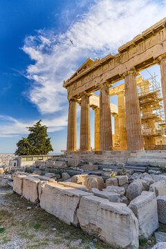 View of the majestic Parthenon under golden light, its ancient Doric columns against a vivid blue sky, amidst weathered ruins, Athens, Central Athens Regional Unit, Greece.