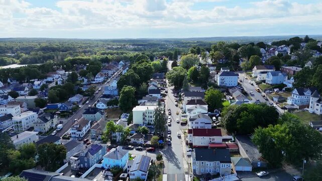 Aerial flyover above Lawrence, Massachusetts on sunny spring day, revealing historic neighborhoods, colorful homes, busy streets and classic New England city charm in urban America. Wide shot.