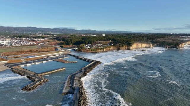 Aerial wide overview of Tomioka Fishing Port, coastline and mountain ranges, Fukushima Japan