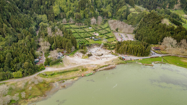 Aerial view of the vibrant green forests surrounding the steaming geothermal hot springs and the calm lake, Ponta Delgada, Azores, Portugal.