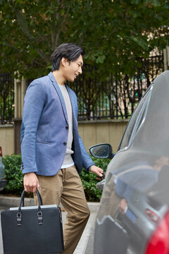 A businessman pulls the car door handle to get in
