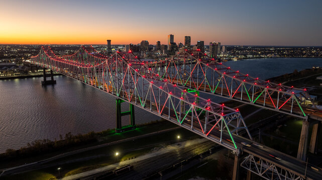 Aerial view of a majestic truss bridge adorned with vibrant red and green lights, spanning dark waters under a twilight sky, Freeport, Texas, United States.
