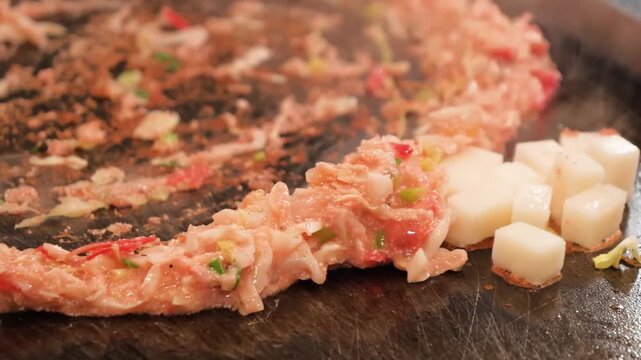 close-up shot of monjayaki being prepared on a hot iron plate. This classic Tokyo specialty features a loose, savory batter mixed with ingredients like cabbage, seafood, and cheese, creating a gooey a