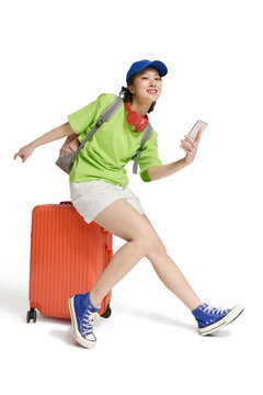 A happy young woman with wheeled luggage,ready for a trip