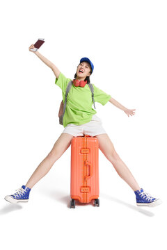 A happy young woman with wheeled luggage,ready for a trip