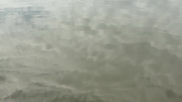 Soft gray cloudscape mirrored on still water, abstract reflection texture background