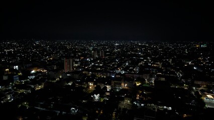 Obraz premium A nighttime view of the city, with a pitch-black sky illuminated by the lights of the surrounding houses.