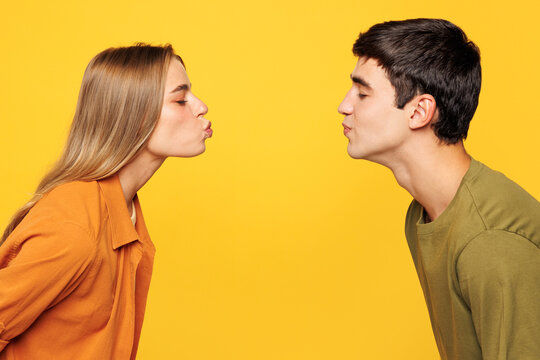 Close up side profile view young lovely couple friends family man woman wear shirt casual clothes together going to kiss each other isolated on pastel plain light yellow background. Lifestyle concept.