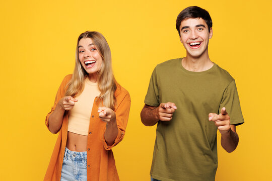 Young fun couple two friends family man woman wear casual clothes point index finger camera on you motivating encourage together isolated on pastel plain light yellow color background studio portrait.
