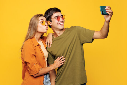 Young couple two friends family man woman wear casual clothes do selfie shot on mobile cell phone post photo on social network together isolated on pastel plain light yellow color background studio