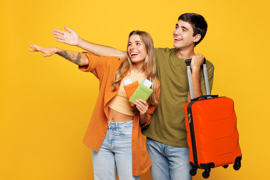 Traveler couple two friend family man woman wear casual clothes hold passport ticket bag isolated on plain yellow background. Tourist travel abroad in free time rest getaway. Air flight trip concept.