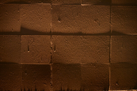 Close up of brown textured concrete wall showing geometric block pattern and rough surface. Supporting construction, architecture, renovation, urban background, copy space use
