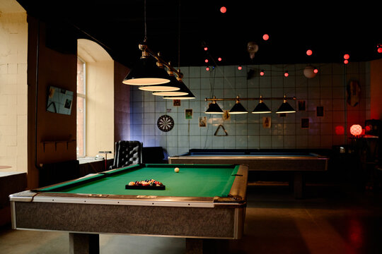 Wide angle shot of billiards tables standing in entertainment venue, showing leisure gaming and nightlife concept. Supporting bar promotion, recreation marketing, event advertising
