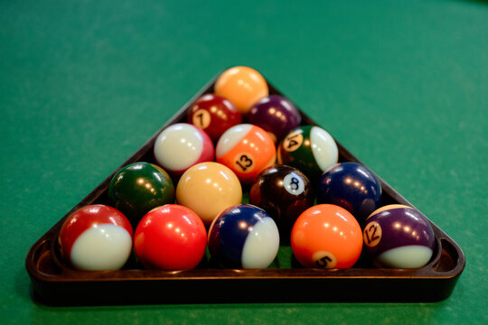 Close up of billiard balls resting in triangle rack on pool table, representing leisure gaming and competition. Suitable for sports club promotion, entertainment ads, or recreation branding
