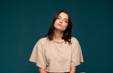 Fototapeta premium Young woman with natural beauty looking at camera against teal background expressing confidence and casual style