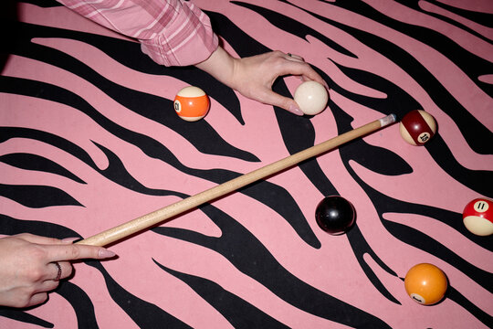 Young adult woman hands positioning cue ball and aiming pool cue on zebra pattern billiards table, suggesting leisure gaming concept. Suitable for nightlife promotion, entertainment branding, social m