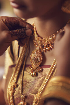 Minimal layout featuring groom placing mangalsutra necklace around bride neck during hindu wedding ritual, intricate jewelry details and mehndi visible, in minimal