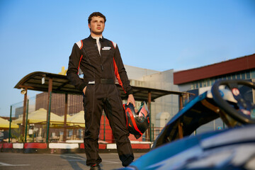 A confident young race car driver stands beside a go-kart © Nomad_Soul