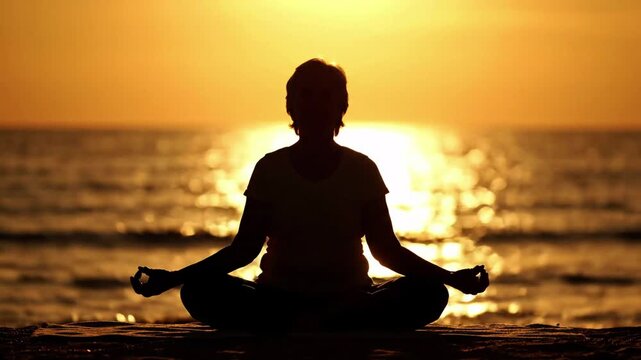 Silhouette of a person meditating in a lotus pose on a beach at sunset, calm ocean waves and golden sunlight reflection, peaceful and mindful, wellness concept