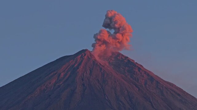 Semeru volcano erupting with a red ash cloud at sunset