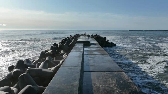 Aerial top-down symmetrical view of breakwater with tetrapods on both sides, Tomioka