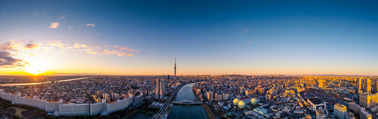 Aerial panorama view by drone of Tokyo Cityscape with Tokyo Sky Tree visible in Tokyo city, Japan on sunrise. Panoramic Dawn view of Tokyo city. Senso-Ji Temple with Sumida river in Japan. © FocusStocker