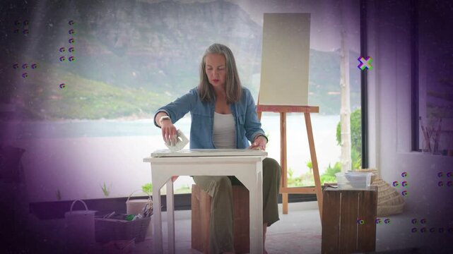 Mature woman placing cloth and smoothing table preparing art surface purple marks obscuring margins