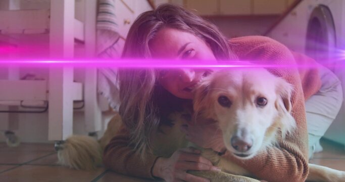 Hugging adult woman cuddling golden dog on tiled kitchen floor, rust sweater and pink lens flare