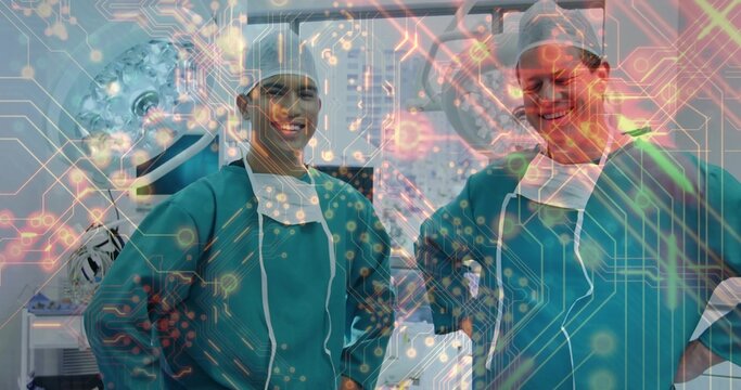 Smiling two surgeons in teal gowns, caps posing in OR, masks-lowered, screens, tech-overlay showing