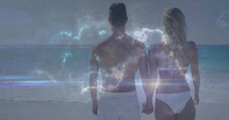 Naklejka premium Holding hands couple facing ocean on shore in white swimwear, starry nebula and lens flare