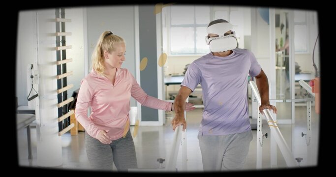 Walking patient wearing white VR headset, purple tee between parallel bars in rehab gym, PT guiding