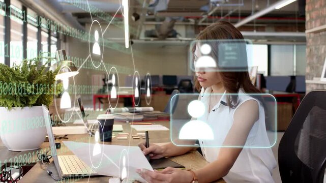 Woman reviewing prints while using stylus, AR profile cards passing around her for design analysis