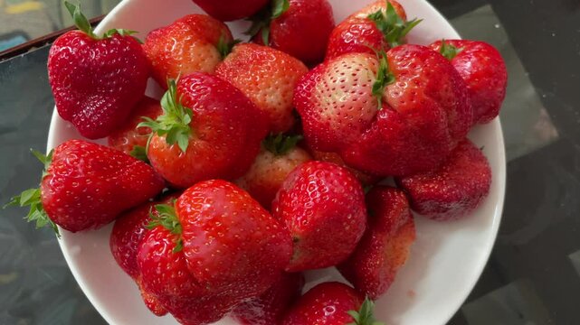 Red strawberries on a plate filmed in Vietnam, showing ripe fruit texture and natural light for dessert, nutrition, and fresh produce concepts.