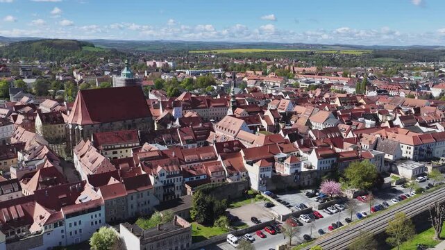 Aerial view of the historic old town of Pirna, Saxony, featuring St. Mary's Church and red-tiled roofs under a blue spring sky.