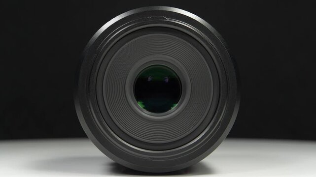 Black macro lens of Micro Four Thirds system, rotates on black background