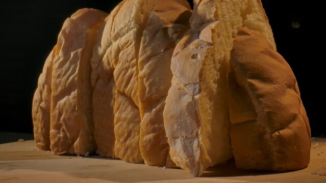 Close up of freshly sliced bread lined up on a wooden surface. Concept of homemade food, bakery products, content for bakeries and bread factories, store, supermarket, gastronomy and culinary art