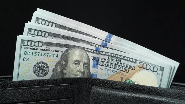 A wad of american dollars in wallet. 100 dollars banknotes in a black wallet. Cash, finance, savings, wealth. New 100 dollar bills, USD