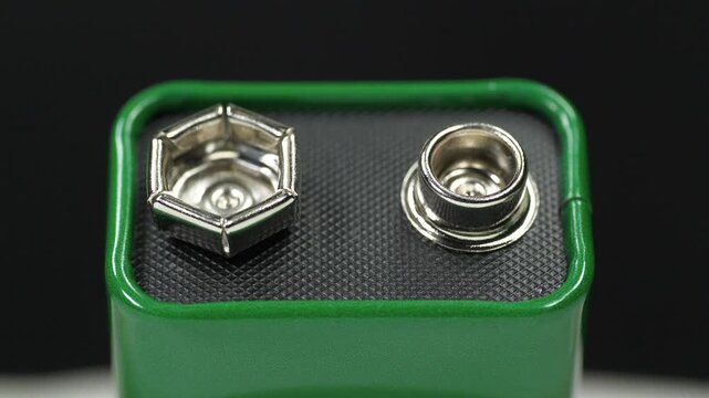 Nine-volt battery, or 9-volt battery - electric battery that supplies a nominal voltage of 9 volts. Green 9-volt battery ready to power devices. Close-up zoom-in video