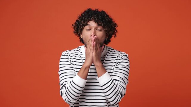 Smiling surprised good kind happy young Indian man he wear striped sweatshirt casual clothes ask who for me oh it so sweet put hands on chest isolated on plain orange red background. Lifestyle concept