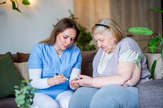 Diabetologist nurse testing blood sample on blood sugar meter.
