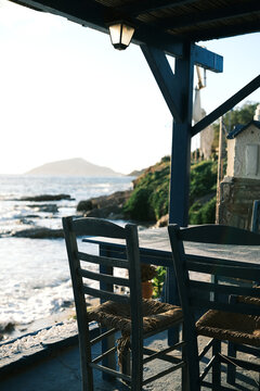 Seaside taverna with chairs and tables overlooking the ocean at sunset