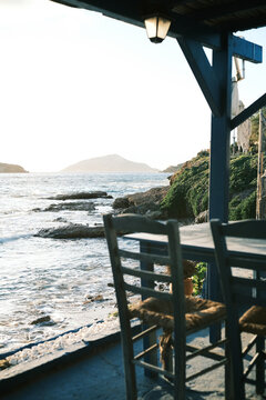 Seaside taverna with chairs and tables overlooking the ocean and distant island