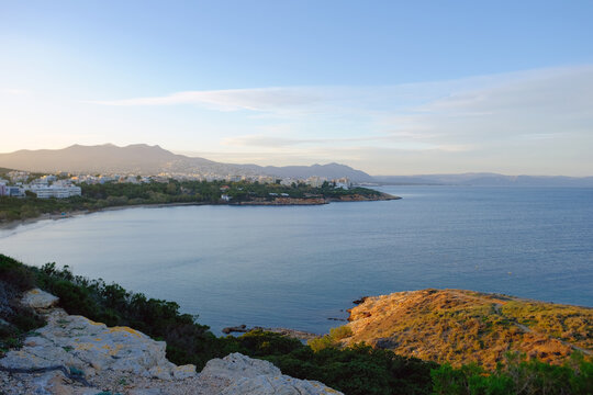 Coastal town nestled beside a tranquil bay with distant mountains under a clear sky
