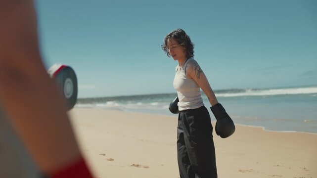 Woman kickboxer training with coach on the beach