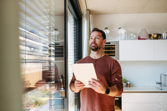 Man using smart home app to control electric window shades indoors.