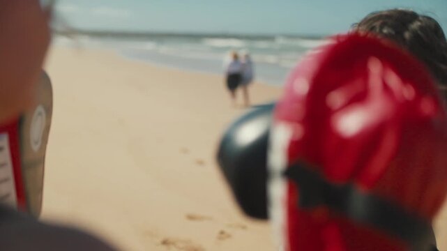 Woman boxer punching focus mitts during training on the beach